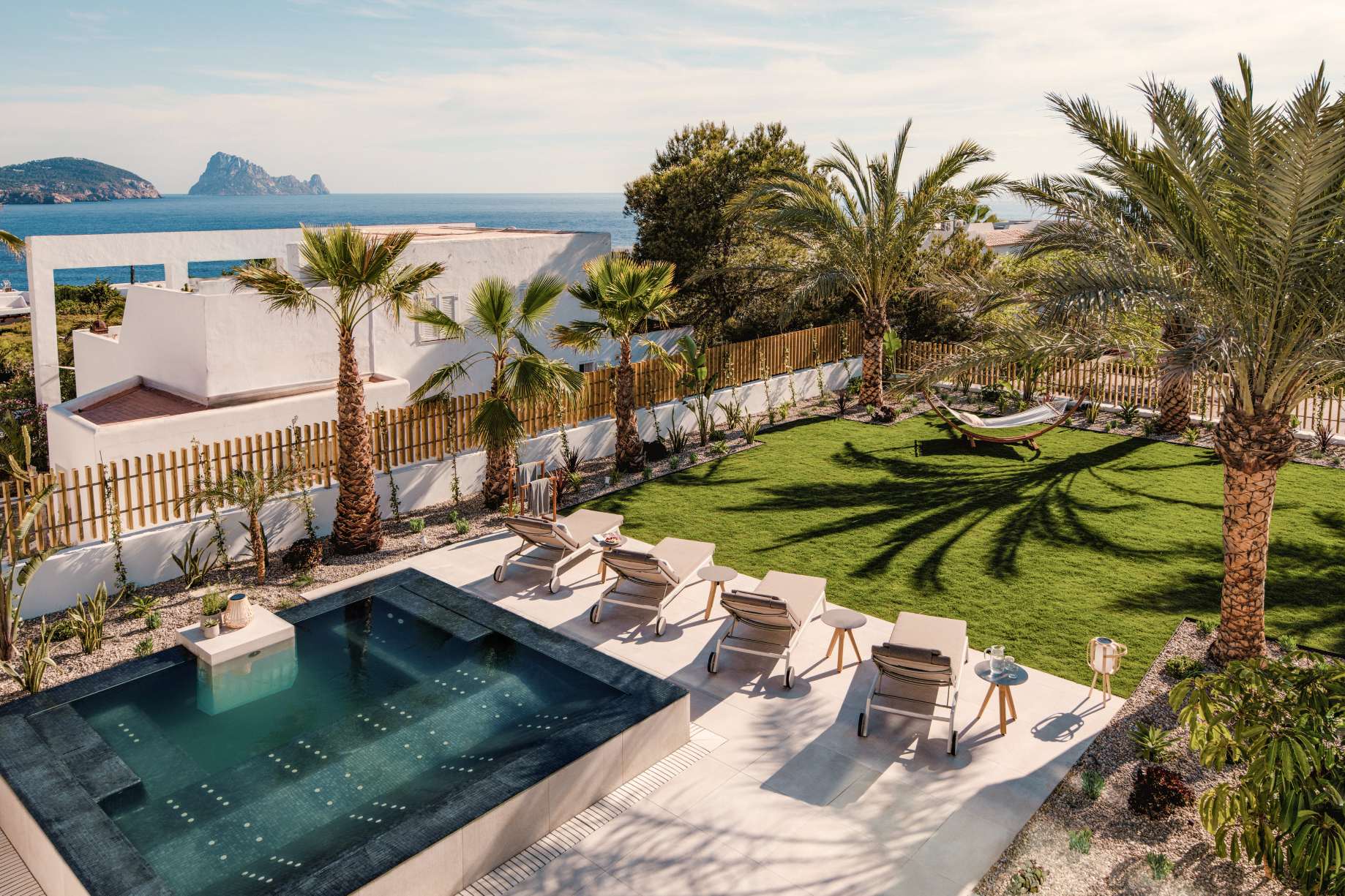 Pool und palmengesäumter Garten in Cala Codolar, Ibiza, mit Blick aufs Meer und Es Vedrà